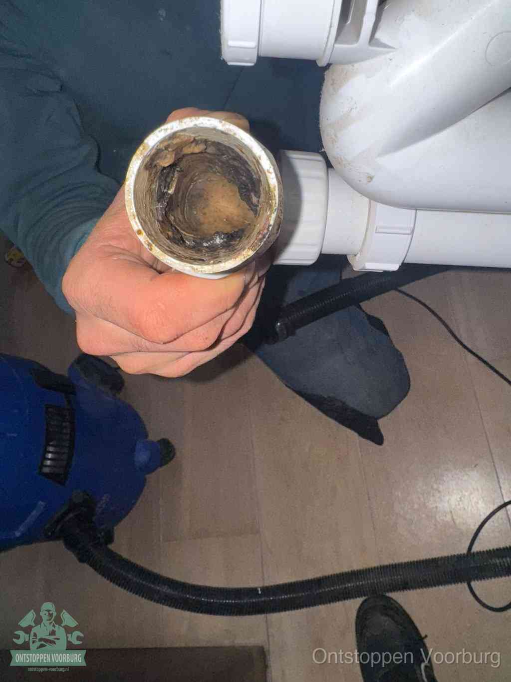 Een losgekoppeld PVC-afvoerbuisstuk dat van binnen volledig is dichtgeslibd met vet en vuil, de meest voorkomende oorzaak van verstoppingen in Voorburg