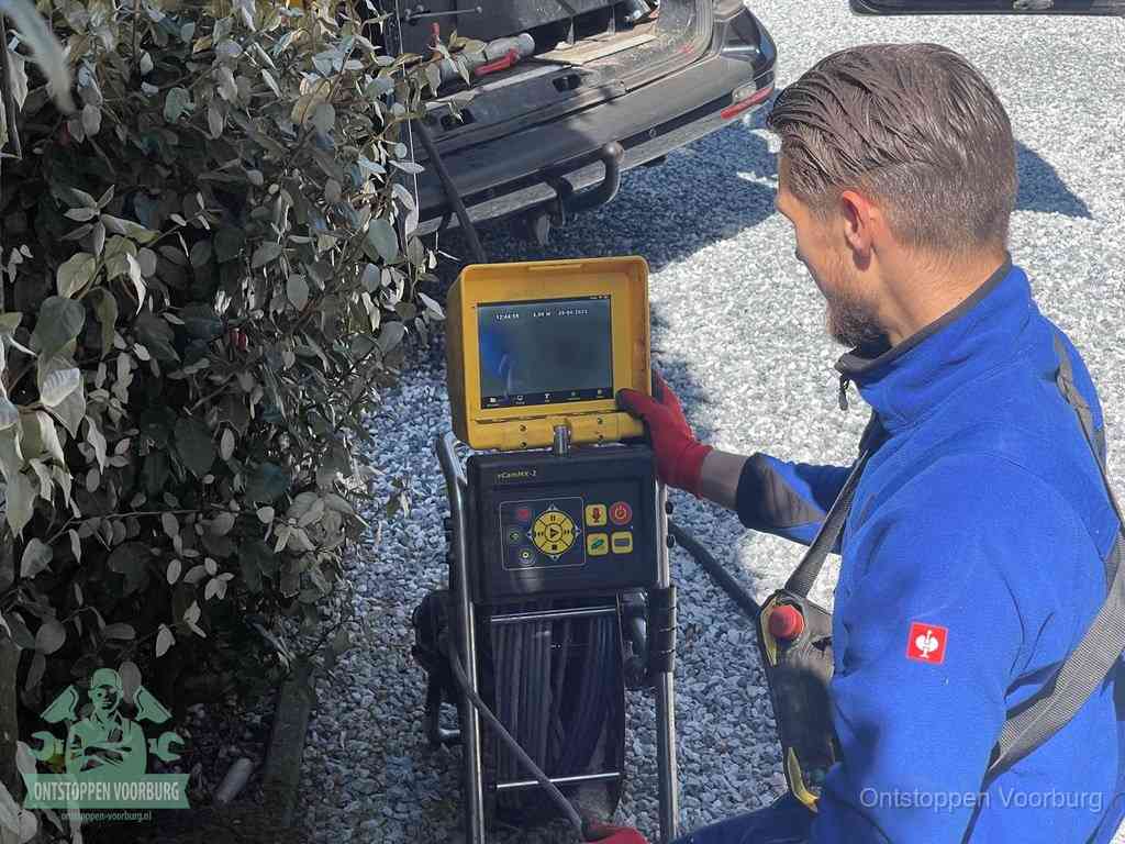 Een monteur bedient een rioolinspectiecamera met monitor en haspel om de verstopping in beeld te brengen in Voorburg