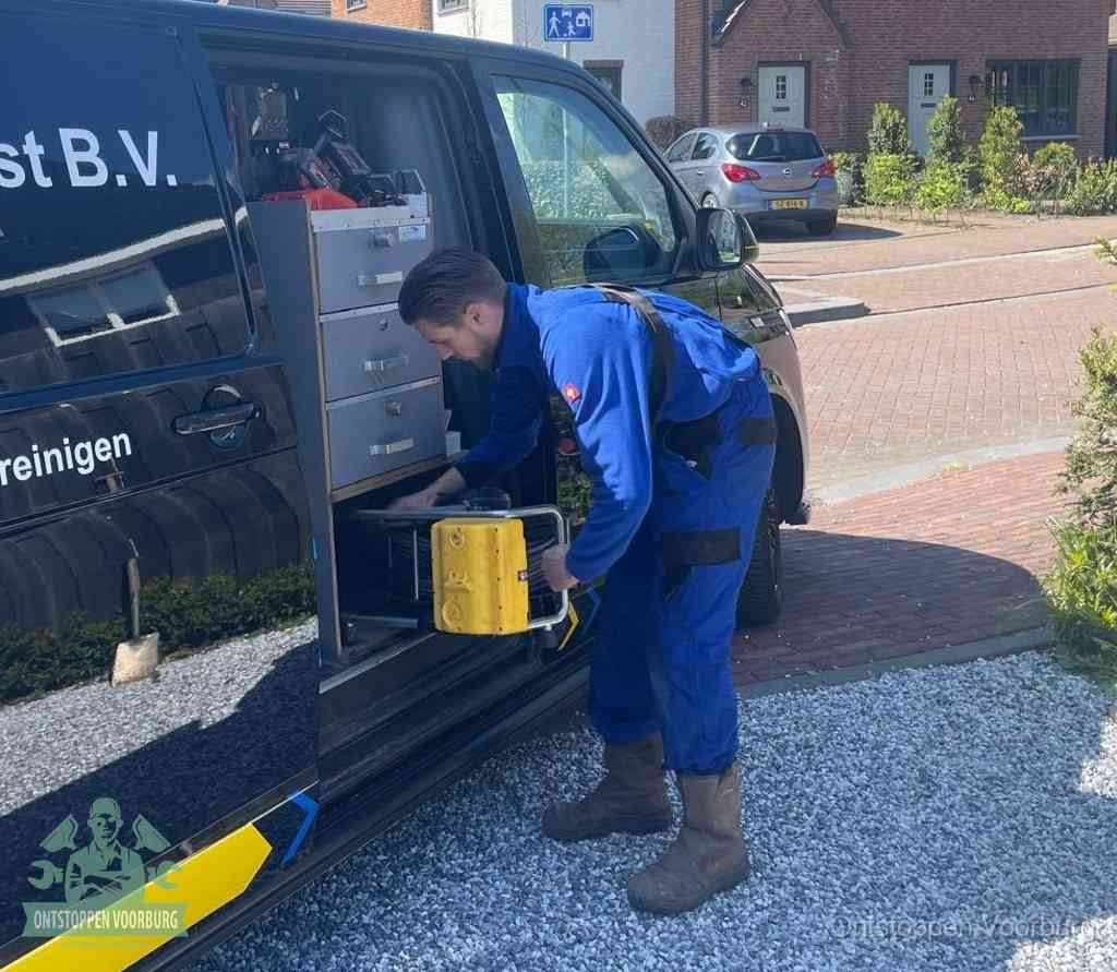 Een monteur pakt gereedschap uit de bedrijfsbus, het moment om een professionele ontstoppingsdienst in te schakelen in Voorburg