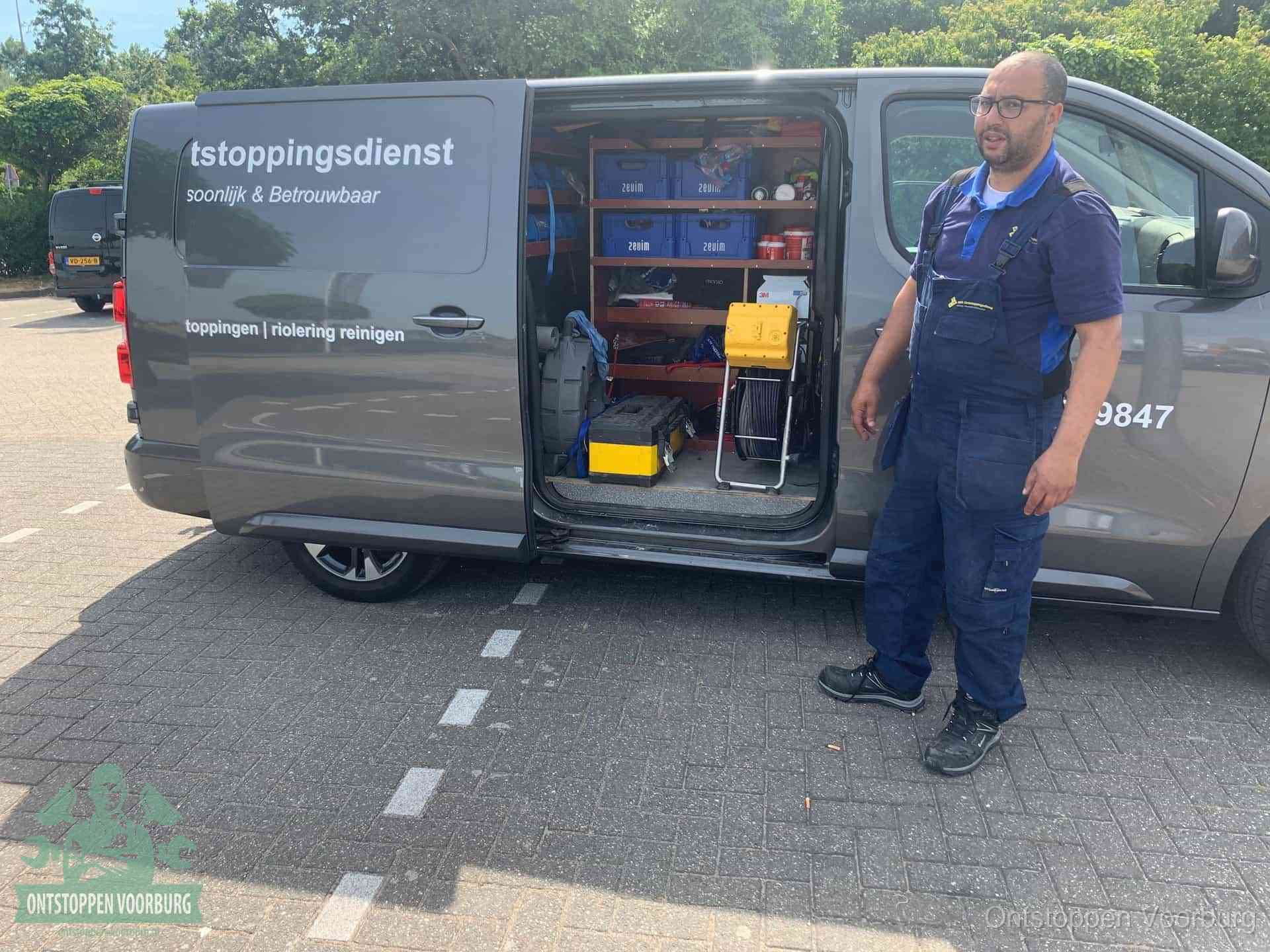 Een monteur staat klaar bij zijn bedrijfsbus met gereedschap, de vaste werkwijze van de ontstoppingsdienst in Voorburg
